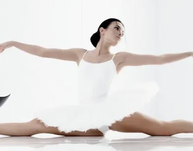 Хрупкая балерина в белоснежной пачке изящно кончает на стуле